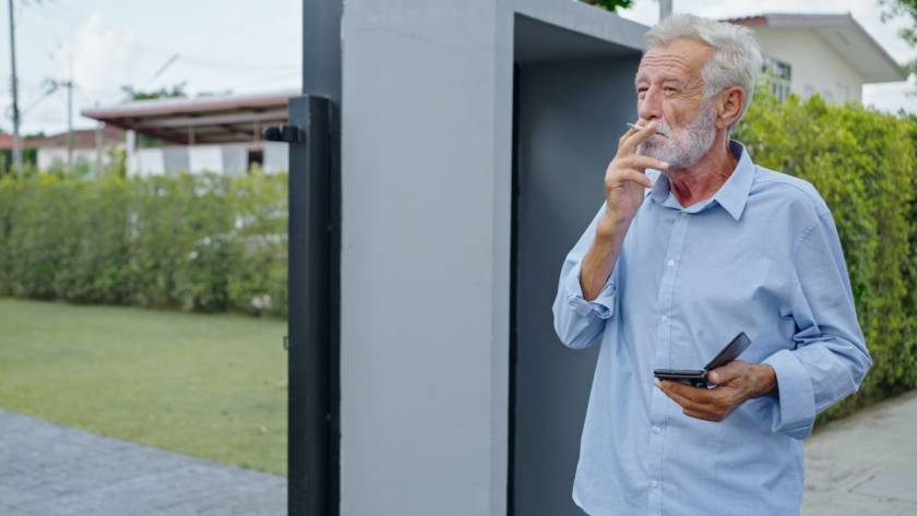 An old senior man smoking cigarette outside, smoke addiction, bad habbit.