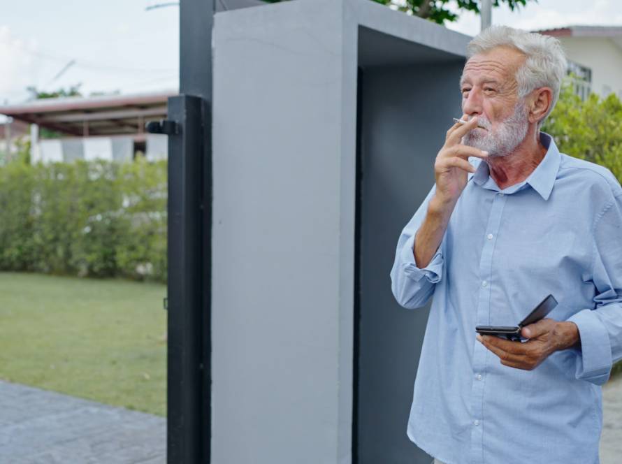 An old senior man smoking cigarette outside, smoke addiction, bad habbit.