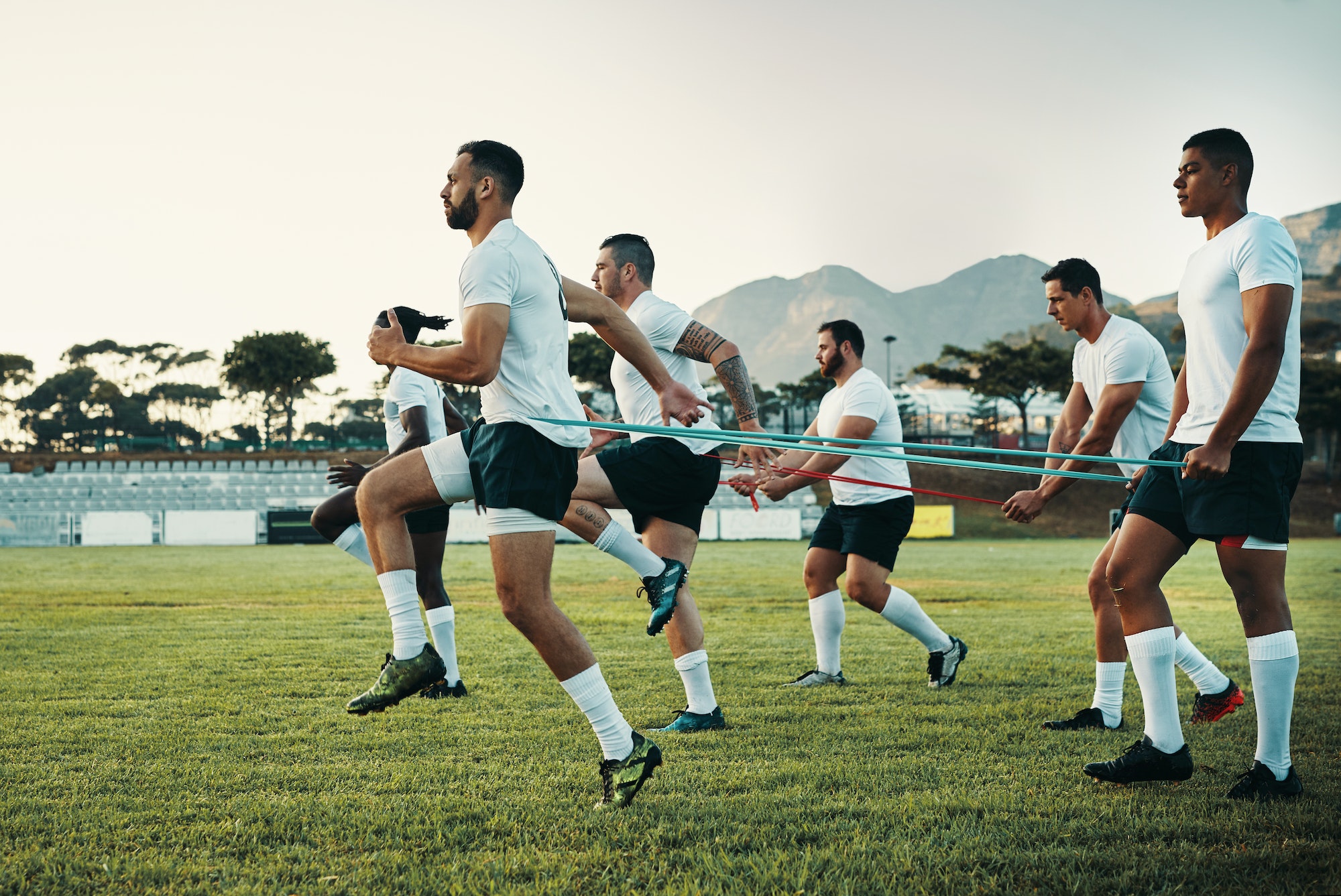 Full length shot of a group of young rugby players training with bands on the field during the day